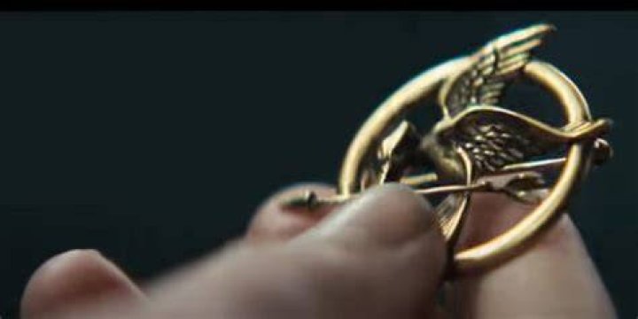How does the Mockingjay pin represent Katniss